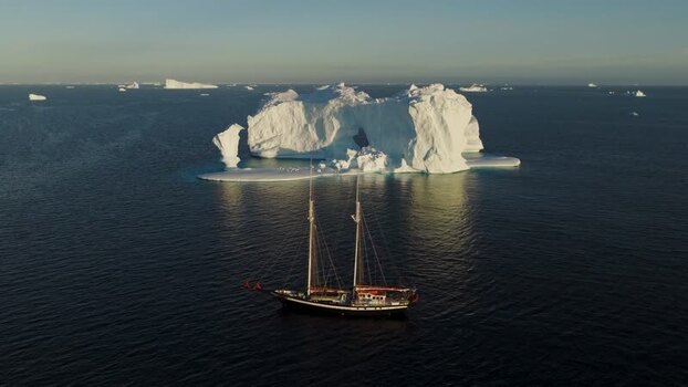 Aerial view of sailboat near arch iceberg in Greenland. Aerial view of sailboat near arch iceberg in Greenland.