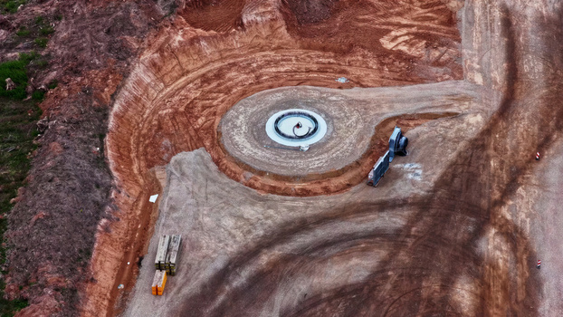 Aerial view of wind turbine foundation under construction with circular concrete base and excavated earth at a site in Latvia. Aerial view of wind turbine foundation under construction with circular concrete base and excavated earth at a site in Latvia.
