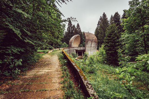 View of the Korcanica Memorial Zone monument on Grmec mountain featuring curved concrete structures surrounded by a dense forest Sanski Most Federation of Bosnia Bosnia and Herzegovina. View of the Korcanica Memorial Zone monument on Grmec mountain featuring curved concrete structures surrounded by a dense forest Sanski Most Federation of Bosnia Bosnia and Herzegovina.