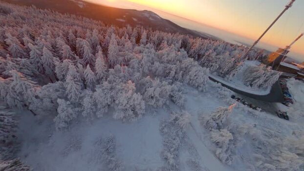 FPV aerial view of snowy forest and tower in Germany.