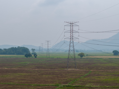 Aerial view of transmission towers standing in agricultural fields with distant hills under a cloudy sky in Bukit Mertajam Penang Malaysia. Aerial view of transmission towers standing in agricultural fields with distant hills under a cloudy sky in Bukit Mertajam Penang Malaysia.