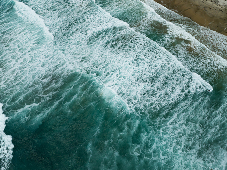Aerial view of turquoise ocean waves crashing onto the sandy shore with white foam and surf at La Jolla Cove in San Diego California United States. Aerial view of turquoise ocean waves crashing onto the sandy shore with white foam and surf at La Jolla Cove in San Diego California United States.