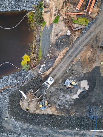 Oulu Finland 18 September 2026 Aerial view of a construction site at the waterfront featuring heavy machinery including an excavator and a dump truck working on gravel ground. Oulu Finland 18 September 2026 Aerial view of a construction site at the waterfront featuring heavy machinery including an excavator and a dump truck working on gravel ground.