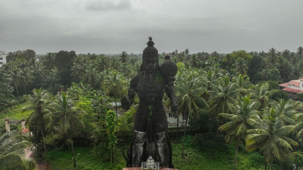 Aerial view of the large Hanuman statue standing amidst lush palm trees and tropical vegetation in Udupi Karnataka India. Aerial view of the large Hanuman statue standing amidst lush palm trees and tropical vegetation in Udupi Karnataka India.