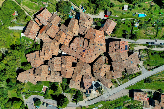 Aerial view of the historic stone houses and terracotta rooftops of Canale di Tenno surrounded by lush green gardens and winding roads Ville del Monte Trentino Alto Adige Italy. Aerial view of the historic stone houses and terracotta rooftops of Canale di Tenno surrounded by lush green gardens and winding roads Ville del Monte Trentino Alto Adige Italy.