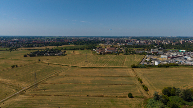 Aerial view of agricultural fields with hay bales power lines and industrial buildings near the urban outskirts of Milan Lombardy Italy. Aerial view of agricultural fields with hay bales power lines and industrial buildings near the urban outskirts of Milan Lombardy Italy.