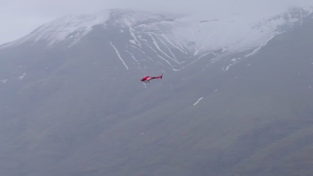 Aerial view of a red helicopter near a snow covered mountain Iceland. Aerial view of a red helicopter near a snow covered mountain Iceland.