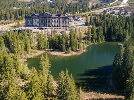 Aerial view of Damian Jasna Hotel Resort and Residences nestled among dense evergreen forests and a calm mountain lake under bright sunlight in Demanovska Dolina Zilinsky kraj Slovakia. Aerial view of Damian Jasna Hotel Resort and Residences nestled among dense evergreen forests and a calm mountain lake under bright sunlight in Demanovska Dolina Zilinsky kraj Slovakia.