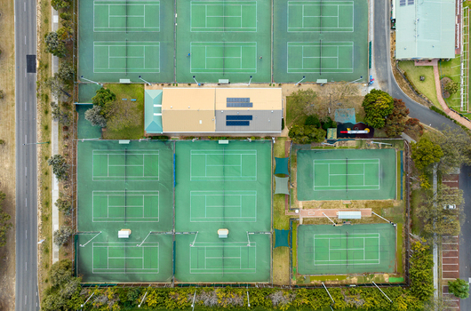 Aerial view of Sorrento Tennis Club featuring multiple green tennis courts a central clubhouse with solar panels and surrounding trees in Duncraig Western Australia Australia. Aerial view of Sorrento Tennis Club featuring multiple green tennis courts a central clubhouse with solar panels and surrounding trees in Duncraig Western Australia Australia.