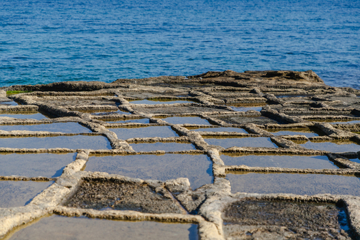 View of the ancient salt pans reflecting the azure sky above the rocky coastline a testament to time and tradition Marsaskala Malta. View of the ancient salt pans reflecting the azure sky above the rocky coastline a testament to time and tradition Marsaskala Malta.