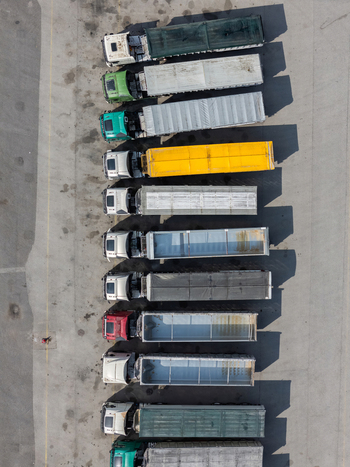 Aerial view of a row of colorful long haul trucks parked in a line on a paved lot in Alges Lisbon Portugal.