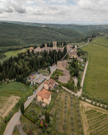 Aerial view of the historic village featuring stone buildings cypress trees and surrounding vineyards under a cloudy sky in Passignano Toscana Italy. Aerial view of the historic village featuring stone buildings cypress trees and surrounding vineyards under a cloudy sky in Passignano Toscana Italy.