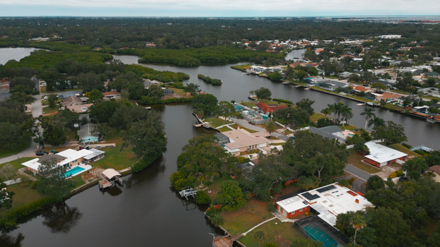 Aerial view of a residential neighborhood with houses swimming pools and canals surrounded by lush mangroves in Clearwater Florida United States.