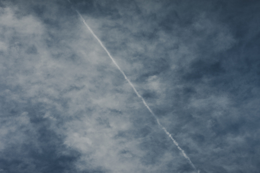 Laane County Estonia 02 June 2024 View of a contrail cutting across a cloudy blue sky over Vormsi.