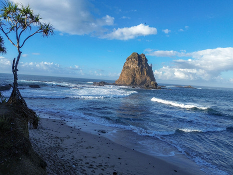 Aerial view of Papuma Beach featuring its iconic rock formation crashing waves and sandy shore under a clear blue sky in Jember East Java Indonesia. Aerial view of Papuma Beach featuring its iconic rock formation crashing waves and sandy shore under a clear blue sky in Jember East Java Indonesia.