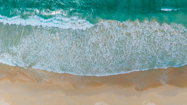 Aerial view of turquoise ocean waves crashing onto the sandy shore of Grand Anse Mahe Seychelles. Aerial view of turquoise ocean waves crashing onto the sandy shore of Grand Anse Mahe Seychelles.