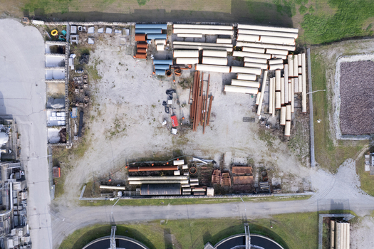 Aerial view of the Waste Water Treatment facility storage yard featuring rows of large industrial pipes construction materials and circular treatment tanks in Richmond British Columbia Canada. Aerial view of the Waste Water Treatment facility storage yard featuring rows of large industrial pipes construction materials and circular treatment tanks in Richmond British Columbia Canada.