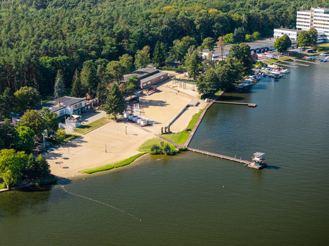 Aerial view of Strandbad Grunau featuring a sandy beach wooden piers extending into the Dahme river surrounding forest and recreational facilities in Berlin Berlin Germany. Aerial view of Strandbad Grunau featuring a sandy beach wooden piers extending into the Dahme river surrounding forest and recreational facilities in Berlin Berlin Germany.