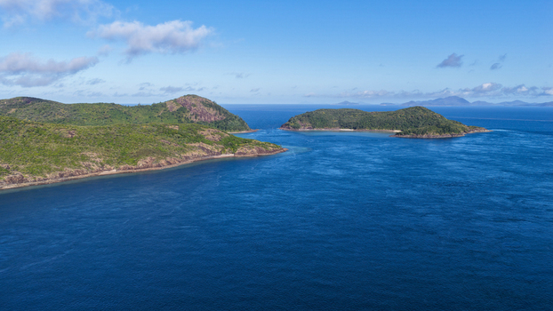 Aerial view of Haslewood Island surrounded by deep blue waters lush green hills and rocky coastlines in Whitsundays Queensland Australia. Aerial view of Haslewood Island surrounded by deep blue waters lush green hills and rocky coastlines in Whitsundays Queensland Australia.