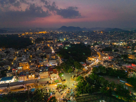 Aerial view of the illuminated cityscape of Udaipur at night with glowing street lights dense urban buildings and distant hills in Udaipur Rajasthan India. Aerial view of the illuminated cityscape of Udaipur at night with glowing street lights dense urban buildings and distant hills in Udaipur Rajasthan India.
