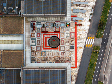 Aerial view of a modern building rooftop featuring geometric patterns and a central octagonal structure with a nearby road in Leccio Toscana Italy. Aerial view of a modern building rooftop featuring geometric patterns and a central octagonal structure with a nearby road in Leccio Toscana Italy.