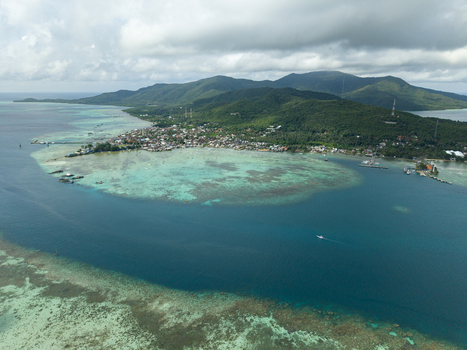 Aerial view of the vibrant turquoise waters surrounding a lush island dotted with buildings a stark contrast to the deep blue sea Karimunjawa Central Java Indonesia. Aerial view of the vibrant turquoise waters surrounding a lush island dotted with buildings a stark contrast to the deep blue sea Karimunjawa Central Java Indonesia.