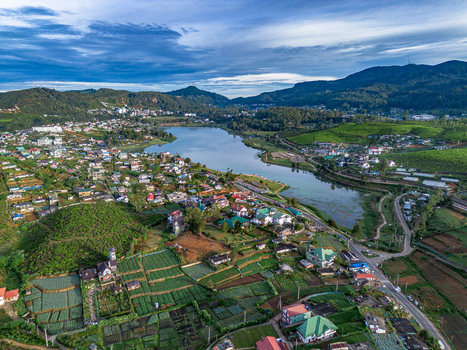 Aerial view of Gregory Lake surrounded by lush green tea plantations residential buildings and rolling hills in Nuwara Eliya Central Province Sri Lanka. Aerial view of Gregory Lake surrounded by lush green tea plantations residential buildings and rolling hills in Nuwara Eliya Central Province Sri Lanka.