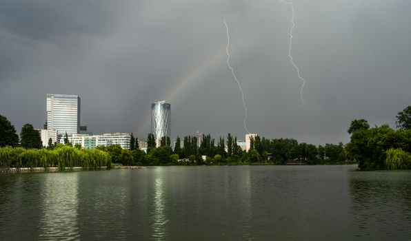 View of lightning strikes and a rainbow over the modern skyline and lake in Bucharest Bucharest Romania. View of lightning strikes and a rainbow over the modern skyline and lake in Bucharest Bucharest Romania.