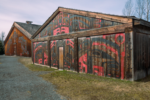 View of traditional Gitxsan longhouses with intricate red and black formline art at Ksan Historical Village in Ksan British Columbia Canada. View of traditional Gitxsan longhouses with intricate red and black formline art at Ksan Historical Village in Ksan British Columbia Canada.