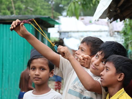 Cox s Bazar Chittagong Division Bangladesh 19 July 2026 View of young boys playing with a slingshot in the Rohingya refugee camp with makeshift shelters in the background.
