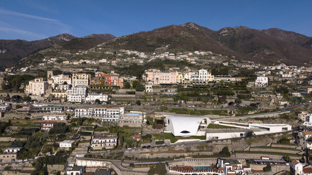 Aerial view of sun kissed buildings cascade and Oscar Niemeyer Auditorium down the hillside towards a modern white structure nestled among green terraces Ravello Salerno Italy Aerial view of sun kissed buildings cascade and Oscar Niemeyer Auditorium down the hillside towards a modern white structure nestled among green terraces Ravello Salerno Italy