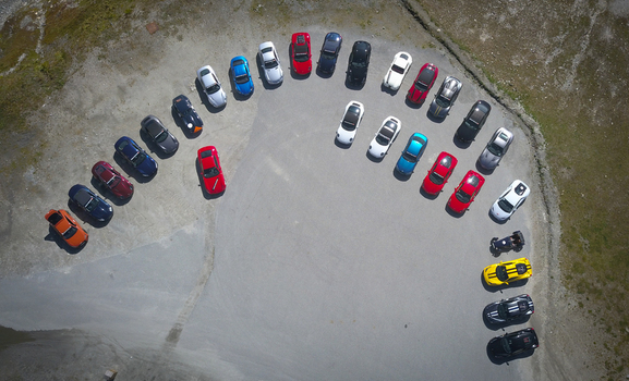Bonneval sur Arc France 28 September 2019 Aerial view of a vibrant array of colorful cars elegantly arranged in a semi circle on a vast textured gray surface like jewels scattered on stone.. Bonneval sur Arc France 28 September 2019 Aerial view of a vibrant array of colorful cars elegantly arranged in a semi circle on a vast textured gray surface like jewels scattered on stone..
