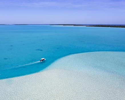 Aerial view of a small boat navigating the turquoise lagoon of Aitutaki Cook Islands. Aerial view of a small boat navigating the turquoise lagoon of Aitutaki Cook Islands.