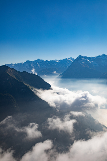Aerial view of the Swiss Alps featuring majestic mountain peaks rising above a thick layer of clouds under a clear blue sky in Airolo Ticino Switzerland. Aerial view of the Swiss Alps featuring majestic mountain peaks rising above a thick layer of clouds under a clear blue sky in Airolo Ticino Switzerland.