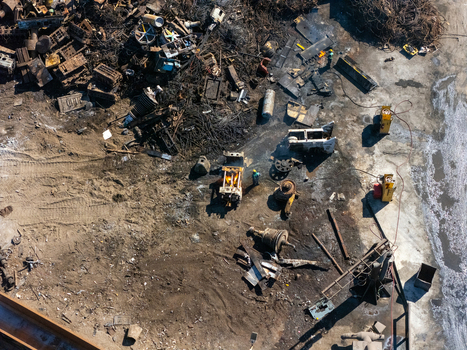 Aerial view of a scrap metal recycling facility with piles of discarded machinery metal debris and industrial equipment with workers in Carson California United States.
