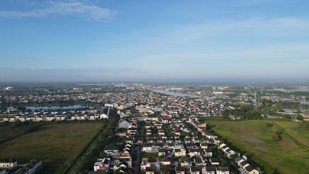 Aerial view of the Jakabaring area featuring dense residential housing green fields and a river winding through the landscape in Kecamatan Seberang Ulu I Sumatera Selatan Indonesia. Aerial view of the Jakabaring area featuring dense residential housing green fields and a river winding through the landscape in Kecamatan Seberang Ulu I Sumatera Selatan Indonesia.