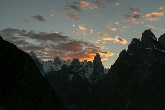 View of the jagged granite spires of the Trango Towers in the Karakoram mountain range at sunset with snow capped peaks and dramatic clouds illuminated by golden light Pakistan. View of the jagged granite spires of the Trango Towers in the Karakoram mountain range at sunset with snow capped peaks and dramatic clouds illuminated by golden light Pakistan.