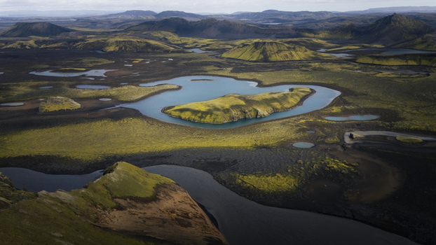 Aerial view of Langisjor lake surrounded by moss covered volcanic terrain dark lava fields and distant mountains in Vik Skaftarhreppur Iceland. Aerial view of Langisjor lake surrounded by moss covered volcanic terrain dark lava fields and distant mountains in Vik Skaftarhreppur Iceland.