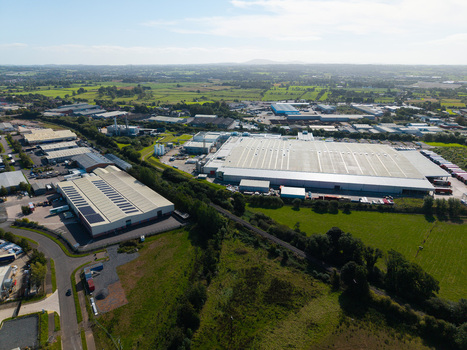 Aerial view of an industrial park with large warehouses flat roofs surrounding green fields and access roads in Lisburn Northern Ireland United Kingdom. Aerial view of an industrial park with large warehouses flat roofs surrounding green fields and access roads in Lisburn Northern Ireland United Kingdom.