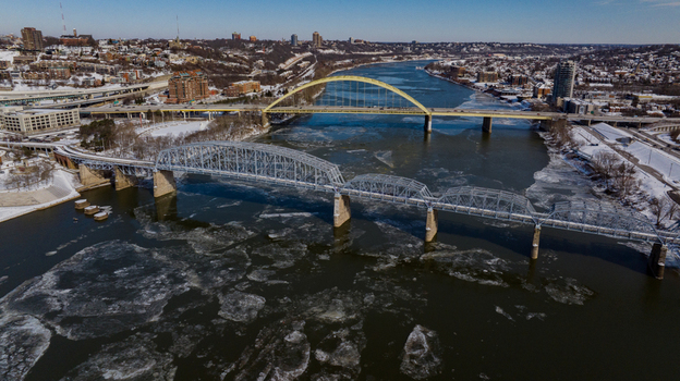 Aerial view of the Daniel Carter Beard Bridge and Taylor Southgate Bridge over the frozen Ohio River with floating ice and snowy banks in Cincinnati Ohio United States. Aerial view of the Daniel Carter Beard Bridge and Taylor Southgate Bridge over the frozen Ohio River with floating ice and snowy banks in Cincinnati Ohio United States.
