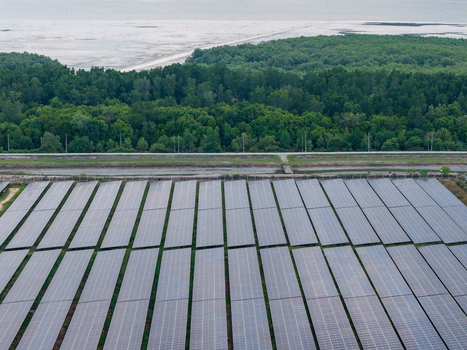 Aerial view of a large scale solar photovoltaic power plant with rows of panels situated next to a dense forest and coastal waters in Central Seberang Perai Penang Malaysia. Aerial view of a large scale solar photovoltaic power plant with rows of panels situated next to a dense forest and coastal waters in Central Seberang Perai Penang Malaysia.