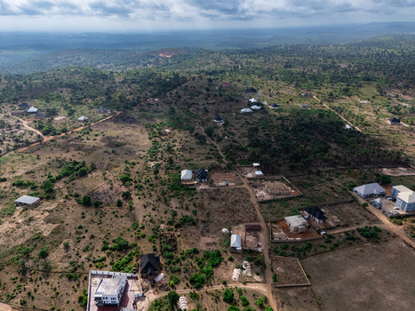 Aerial view of scattered modern homes and developing plots amidst dry earthy tones and sparse green foliage under a dramatic sky Elu Abia Nigeria. Aerial view of scattered modern homes and developing plots amidst dry earthy tones and sparse green foliage under a dramatic sky Elu Abia Nigeria.