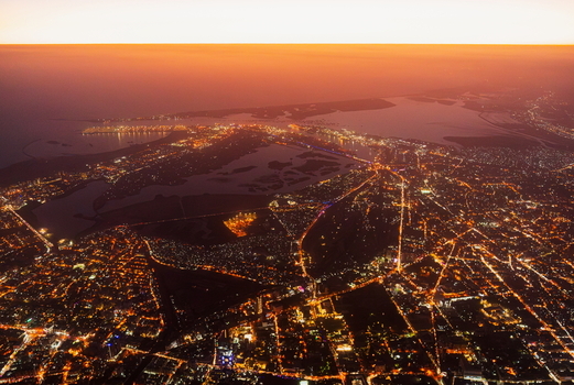 Aerial view of the sprawling urban landscape illuminated at night with glowing city lights and coastal waters Karachi Sindh Pakistan.