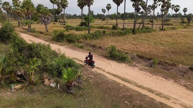Aerial view of a motorcyclist on a rural dirt road Cambodia. Aerial view of a motorcyclist on a rural dirt road Cambodia.