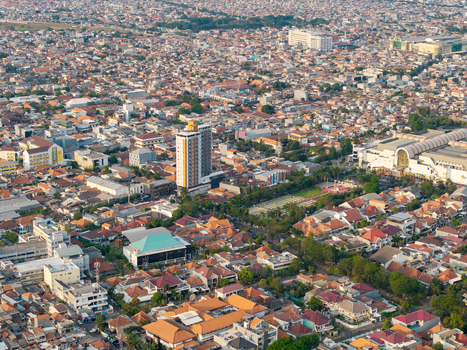 Surabaya Indonesia 28 August 2026 Aerial view of the dense urban landscape of Surabaya East Java featuring a mix of residential rooftops a prominent high rise building and a large commercial complex.