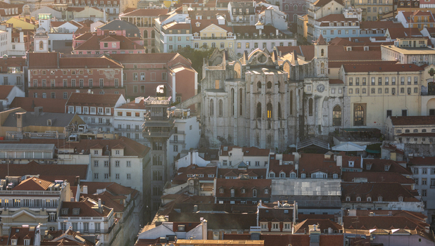 Aerial view of the historic Carmo Convent ruins and the Santa Justa Lift surrounded by traditional terracotta rooftops in the city center of Lisbon Lisbon Portugal.