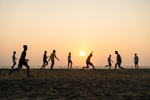 View of a group of people playing football on a sandy beach during a vibrant sunset in Galle Southern Province Sri Lanka.