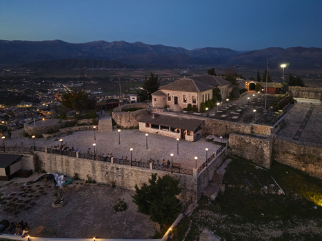 Aerial view of Lekuresi Castle at dusk with illuminated stone walls a central courtyard and the town of Saranda in the background Saranda Vlore County Albania. Aerial view of Lekuresi Castle at dusk with illuminated stone walls a central courtyard and the town of Saranda in the background Saranda Vlore County Albania.