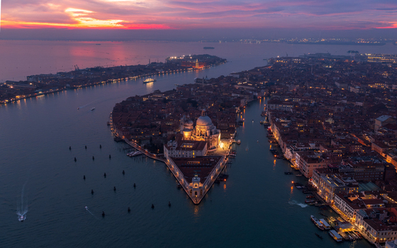 Aerial view of the Basilica di Santa Maria della Salute at sunset with the Grand Canal historic rooftops and boats in the surrounding lagoon in Venice Veneto Italy. Aerial view of the Basilica di Santa Maria della Salute at sunset with the Grand Canal historic rooftops and boats in the surrounding lagoon in Venice Veneto Italy.