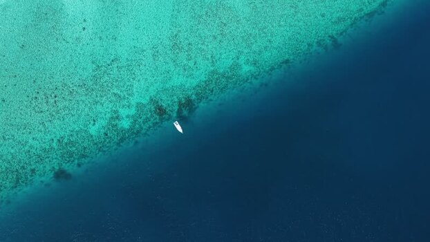 Aerial view of a boat on a coral reef drop off Maldives.